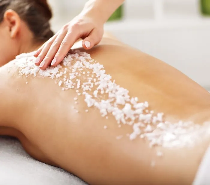 a woman laying on a table getting a salt scrub treatment