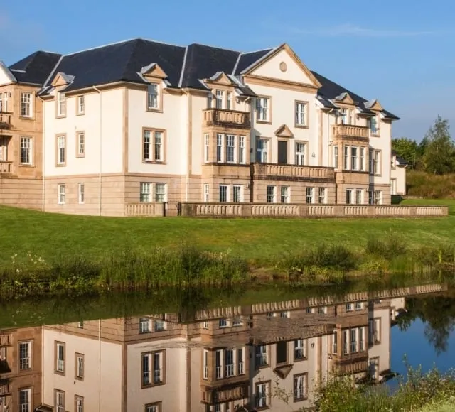 Exterior of Loch Lomond Apartments reflected in a nearby pond.