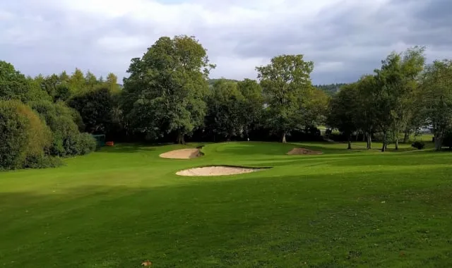 golf course with sand pits surrounding the hole and trees along the edges