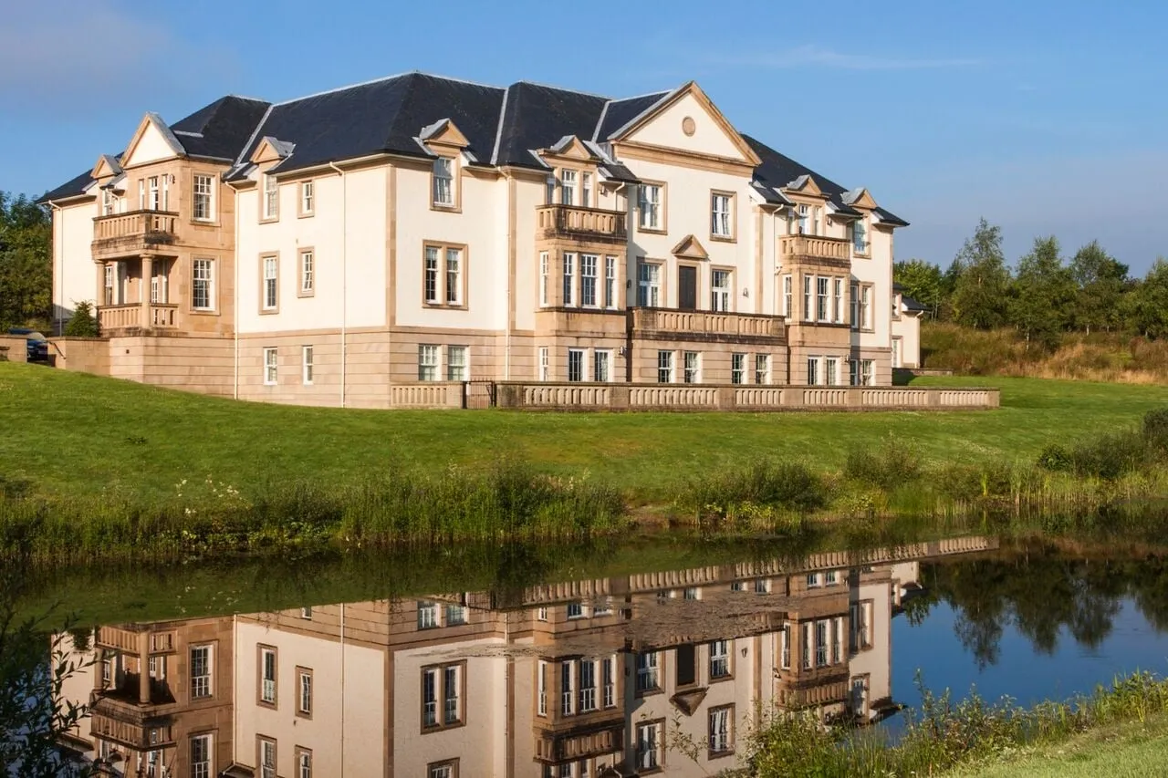 Exterior of Loch Lomond Apartments reflected in a nearby pond.