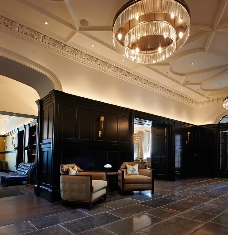 A grand foyer at Cameron House showcasing a large room with a magnificent chandelier hanging from the ceiling.