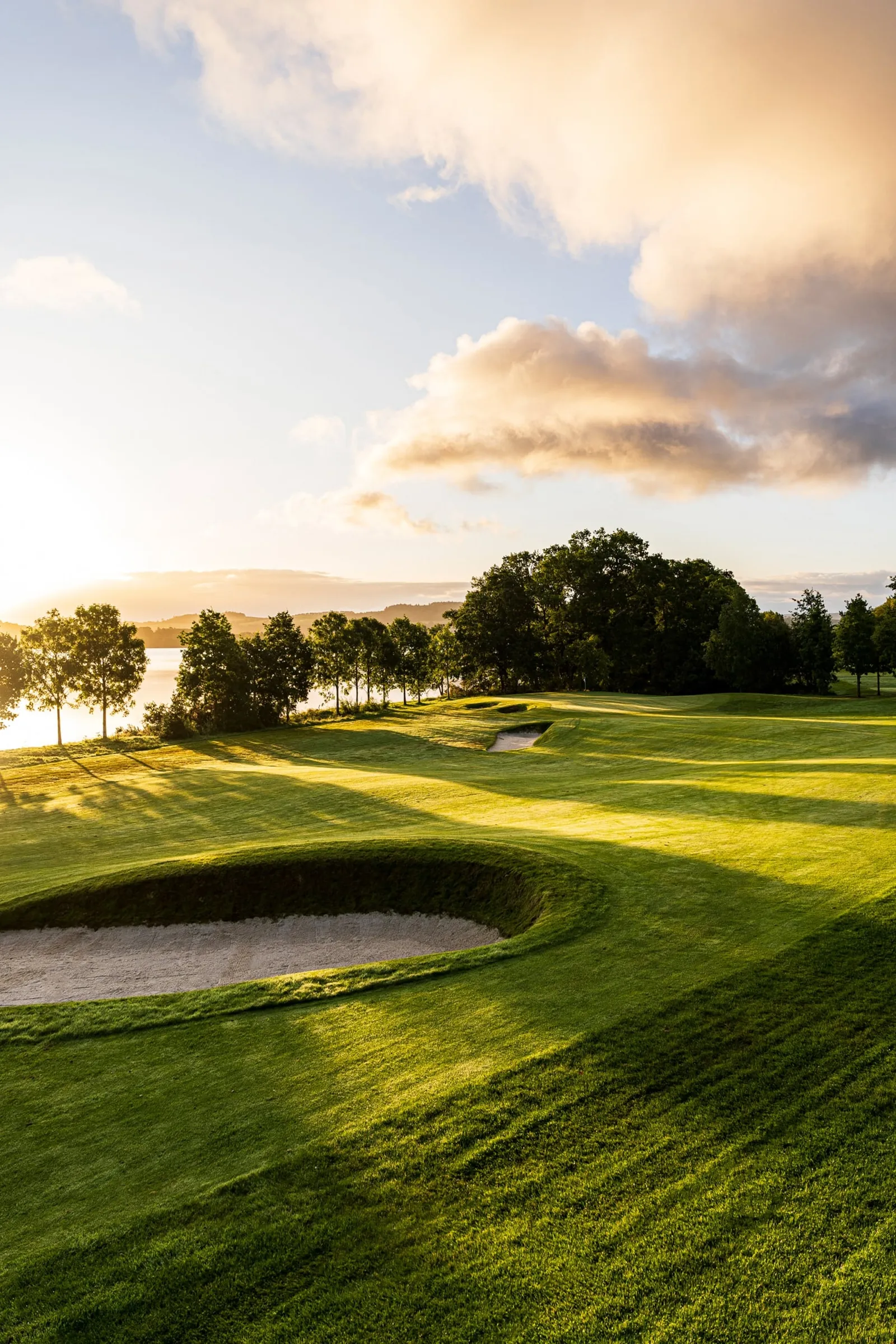 golf course with some sand pits in the middle and trees along the out side