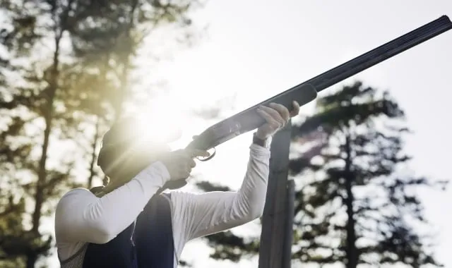 a man holding a shotgun shooting clay targets