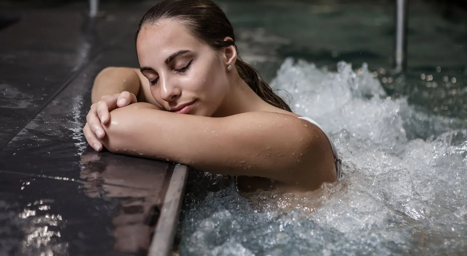a woman in a pool leaning against the side of the pool with her eyes closed